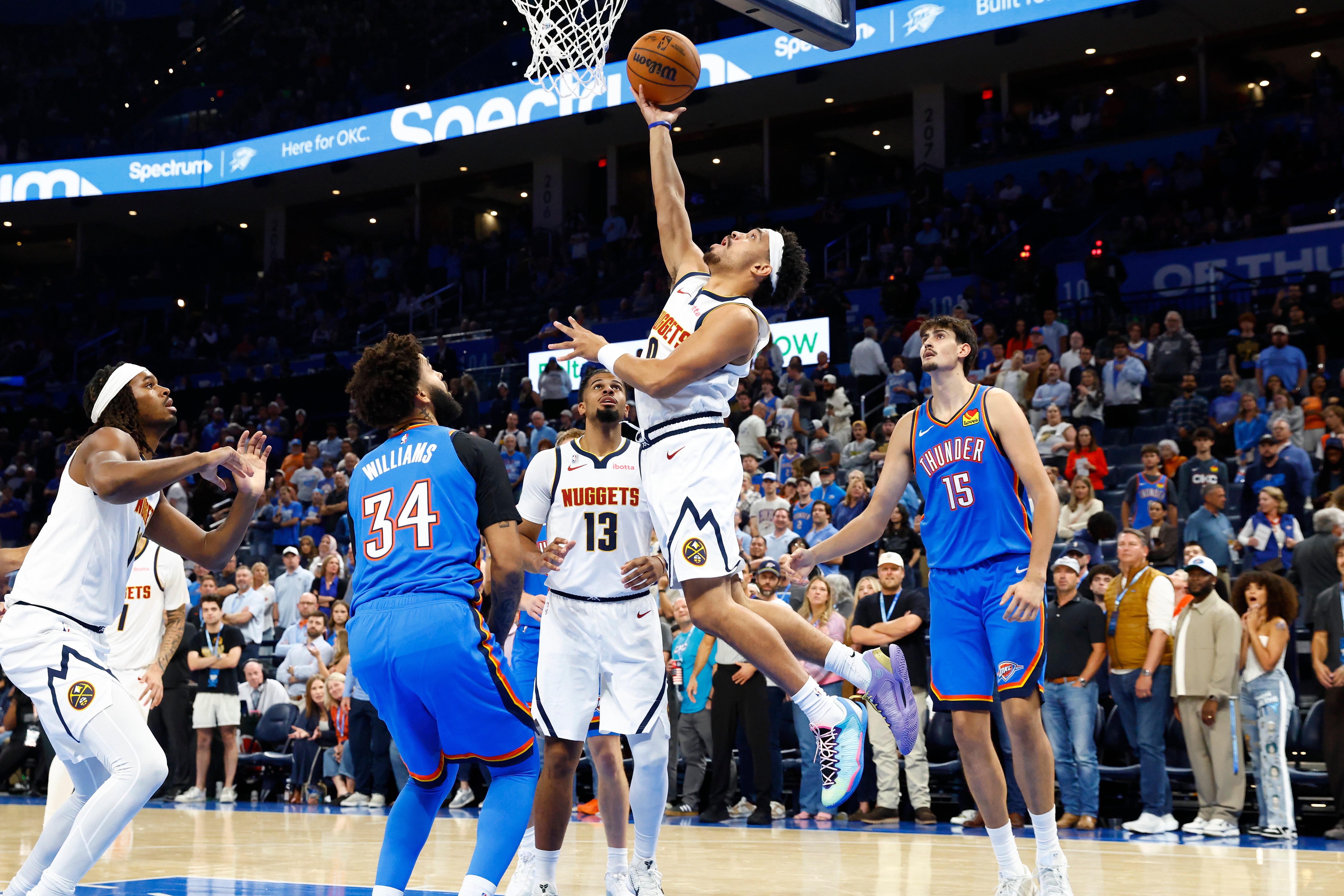 Oct 22, 2026; Oklahoma City, Oklahoma, USA; Denver Nuggets guard Ryan Nembhard (9) goes up for a basket between Oklahoma City Thunder guard Kenrich Williams (34) and center Aday Mara (15) during the second half at Paycom Center. Mandatory Credit: Alonzo Adams-Imagn Images