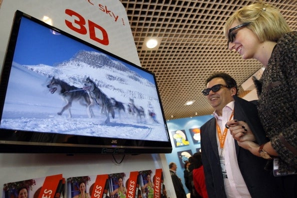 Two people wearing 3D glasses watch huskies on a snowy mountain broadcast on a 3D TV at an event