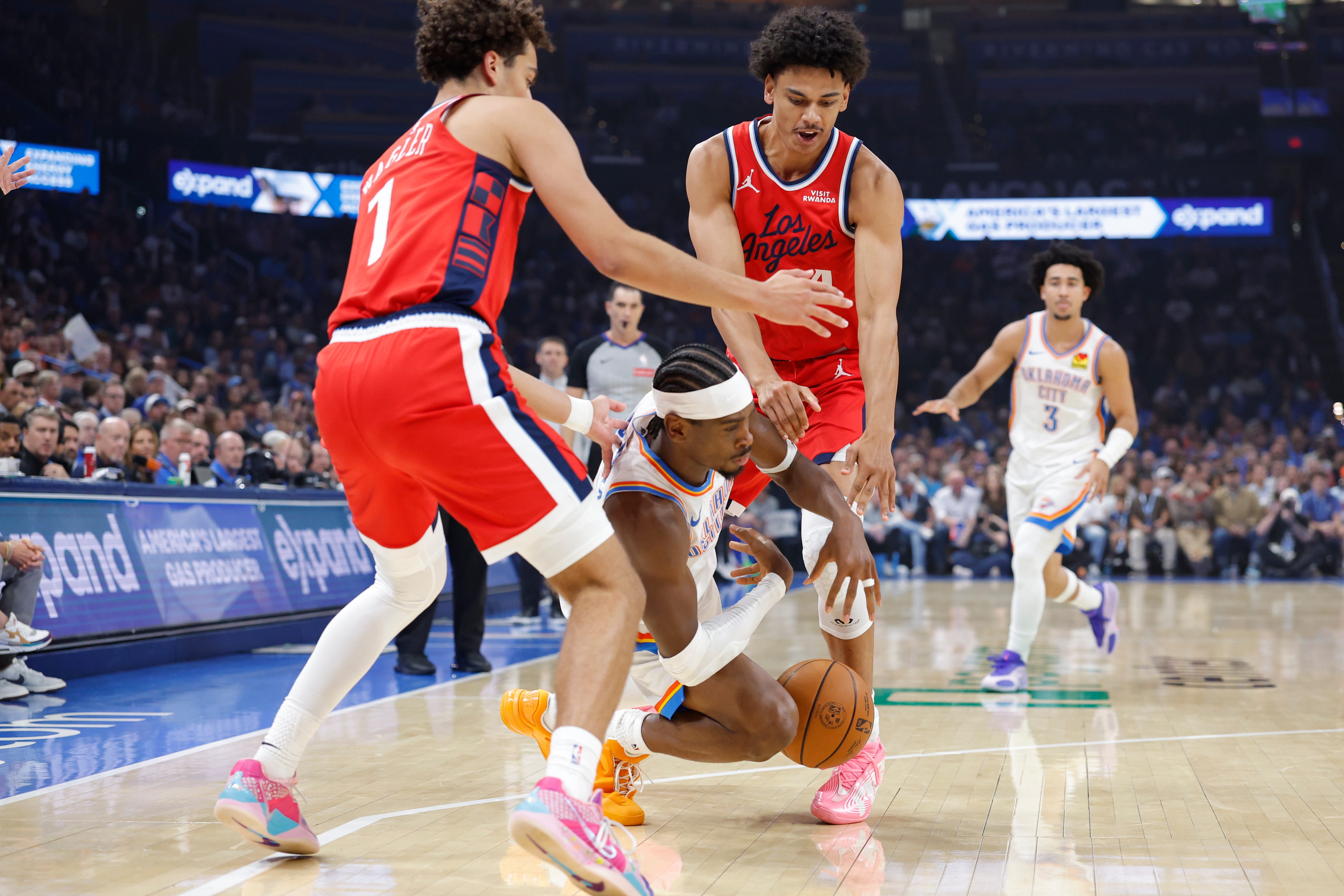 Oct 25, 2026; Oklahoma City, Oklahoma, USA; Oklahoma City Thunder guard Shai Gilgeous-Alexander (2) falls to the ground between Los Angeles Clippers guard Keaton Wagler (1) and guard Kobe Sanders (4) during the first half at Paycom Center. Mandatory Credit: Alonzo Adams-Imagn Images