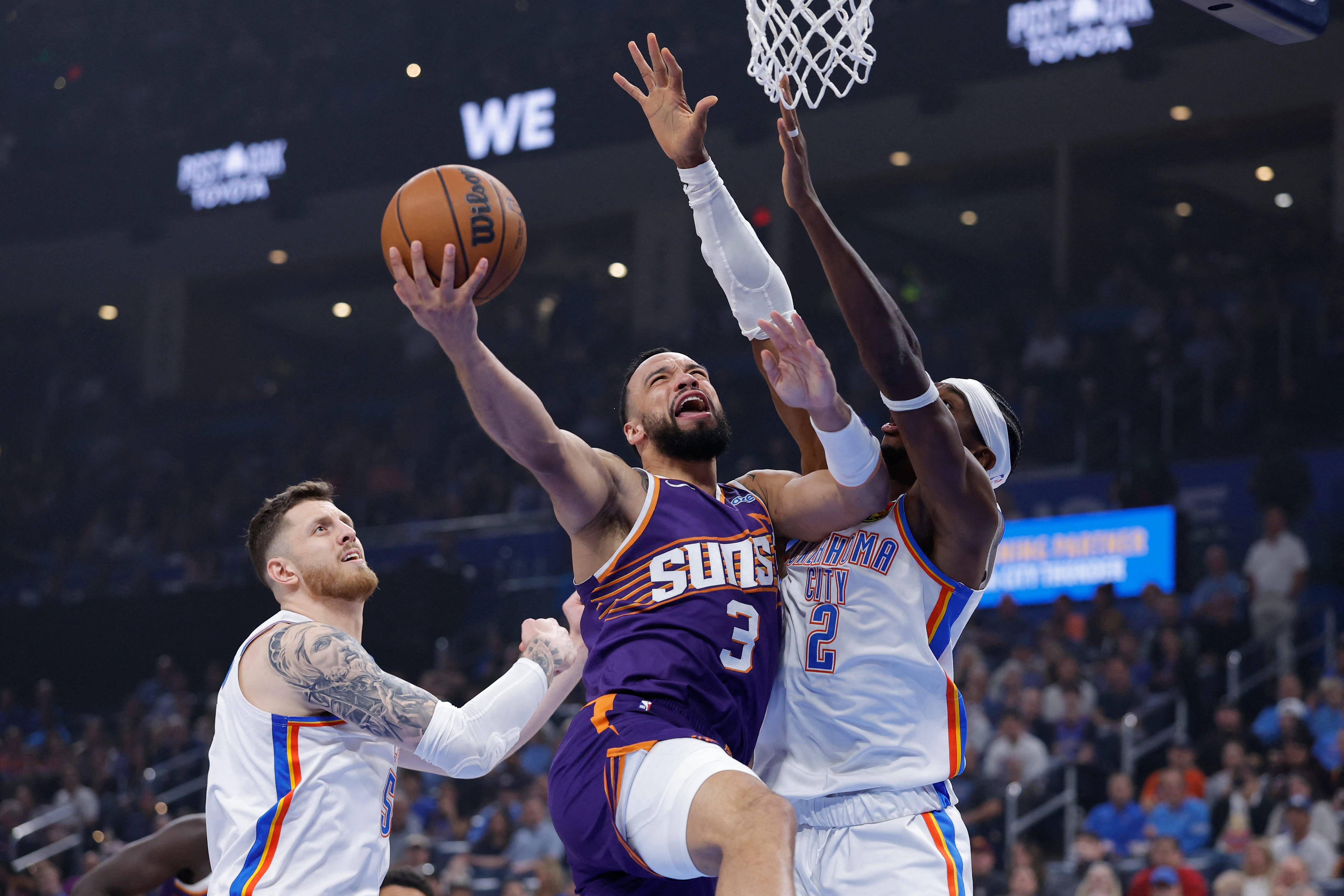 Oct 26, 2026; Oklahoma City, Oklahoma, USA; Phoenix Suns forward Dillon Brooks (3) goes up for a basket between Oklahoma City Thunder center Isaiah Hartenstein (55) and guard Shai Gilgeous-Alexander (2) during the first half at Paycom Center. Mandatory Credit: Alonzo Adams-Imagn Images